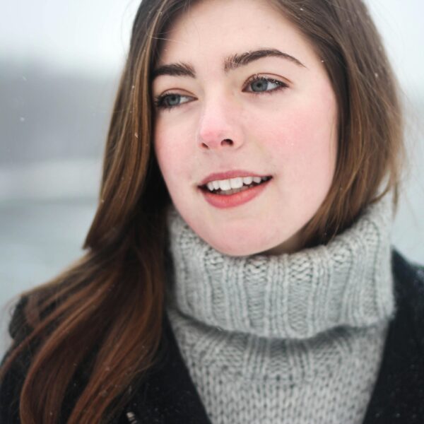 Close-up portrait of a young woman smiling outdoors in the snowy winter.